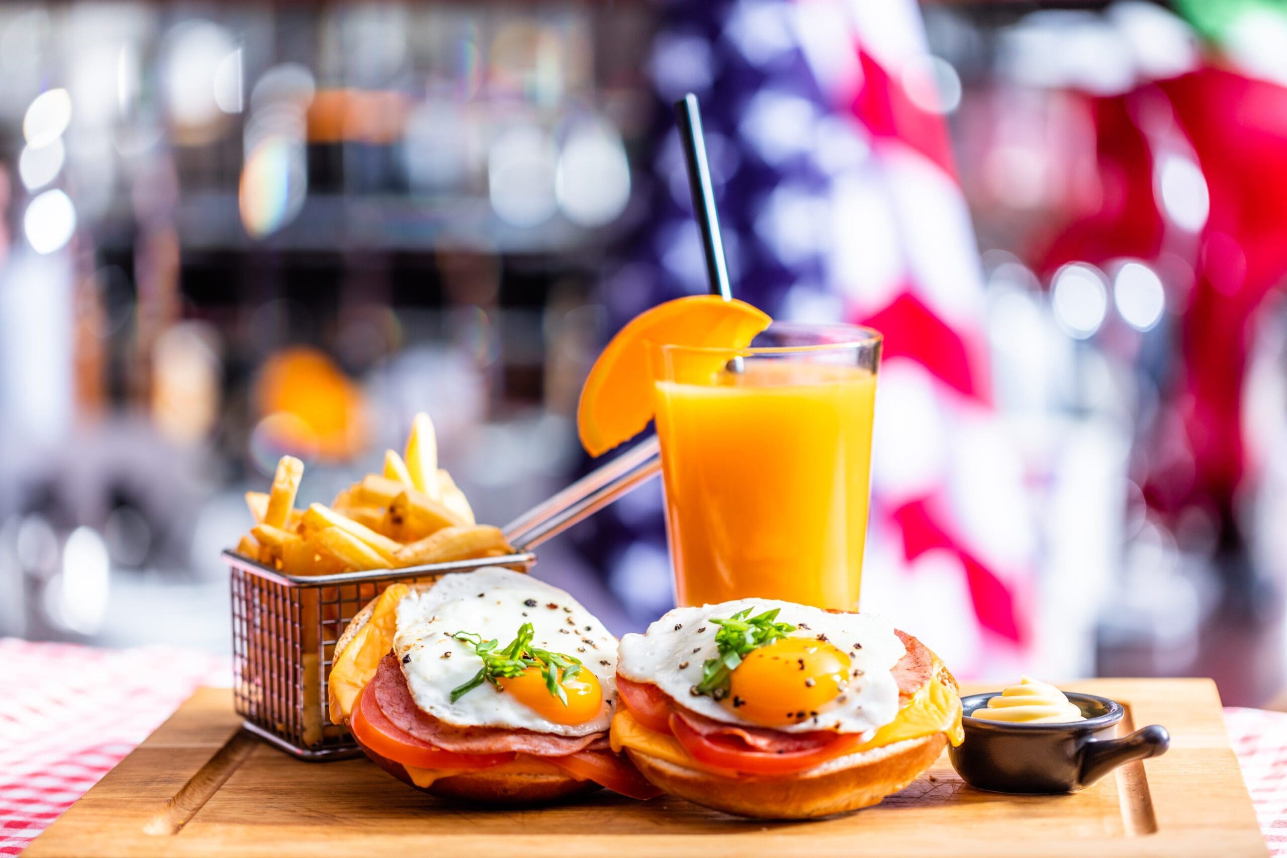 American breakfast, sandwich with fried egg, french fries and orange juice